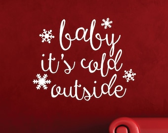 以下が含まれることがあります： 赤い壁に「baby it's cold outside」の文字と雪の結晶が描かれた白いビニール製の壁用ステッカーです。