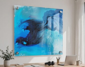 May include: A square glass wall art piece featuring an abstract fluid design in shades of deep navy, royal blue, and bright cyan. The artwork is mounted with four silver-toned metal standoffs at each corner, creating a floating effect on the wall.