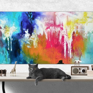 K&ouml;nnte beinhalten: Abstraktes Gem&auml;lde mit leuchtenden Farben in Blau, Gr&uuml;n, Gelb, Orange, Rosa und Wei&szlig;. Eine graue Katze liegt auf einem Tisch vor dem Gem&auml;lde. Auf dem Tisch stehen kleine Tierfiguren.