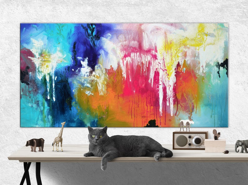 K&ouml;nnte beinhalten: Abstraktes Gem&auml;lde mit leuchtenden Farben in Blau, Gr&uuml;n, Gelb, Orange, Rosa und Wei&szlig;. Eine graue Katze liegt auf einem Tisch vor dem Gem&auml;lde. Auf dem Tisch stehen kleine Tierfiguren.