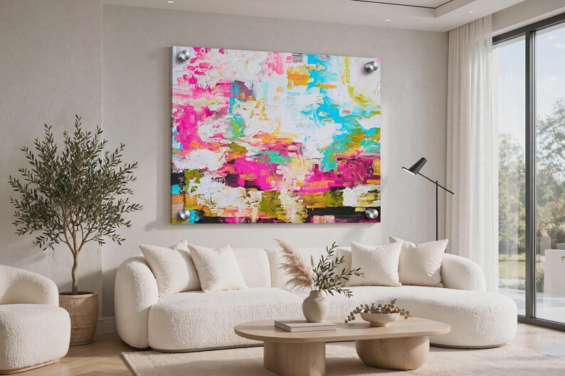 May include: A large rectangular wall art piece featuring an abstract painting with vibrant splashes of hot pink, bright turquoise, sunny yellow, and white. The artwork is mounted with four silver circular standoffs at each corner of the frame.