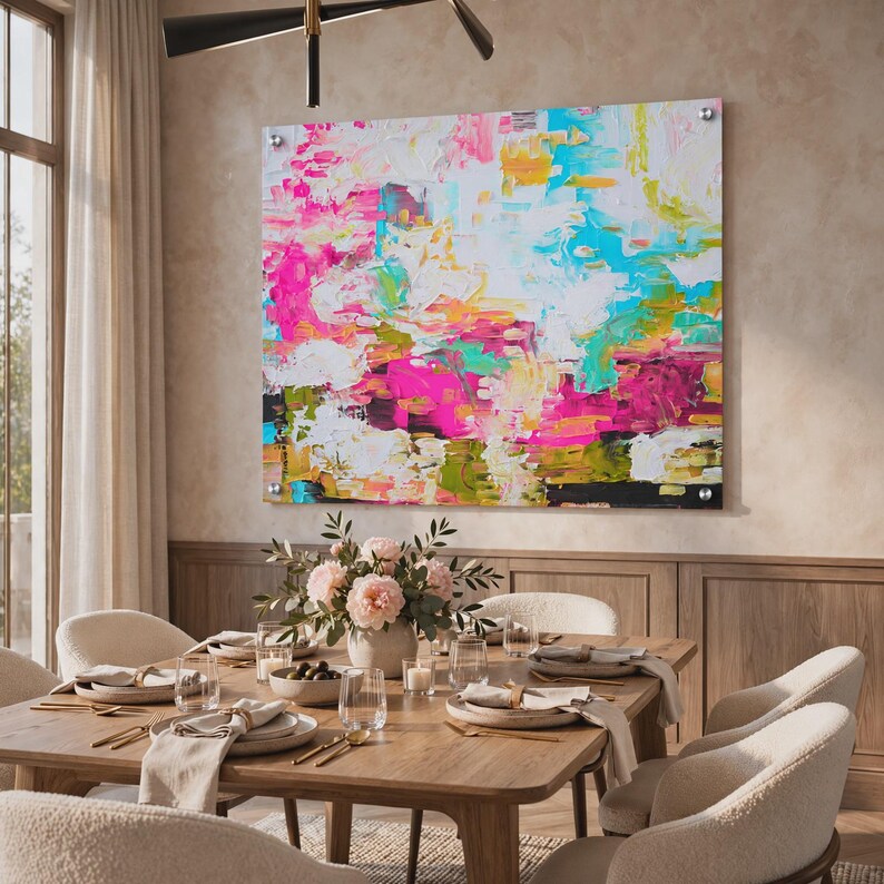 May include: A large square abstract painting featuring thick, textured brushstrokes in vibrant shades of hot pink, bright turquoise, sunny yellow, and white, mounted on a wall with four silver metal standoffs at each corner of the canvas.