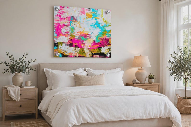 May include: A square acrylic wall art piece featuring an abstract painting with vibrant splashes of hot pink, bright turquoise, sunny yellow, and deep black against a white background, mounted with four silver circular hardware standoffs.