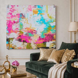 May include: A large square abstract painting featuring thick, textured brushstrokes in vibrant shades of hot pink, turquoise, bright yellow, and white. The artwork is mounted on the wall with four silver metal standoffs at each corner.