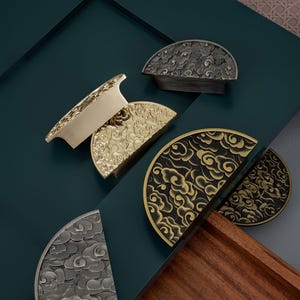 May include: Four half-circle cabinet knobs with a cloud design. The knobs are in three finishes: gold, black, and silver.