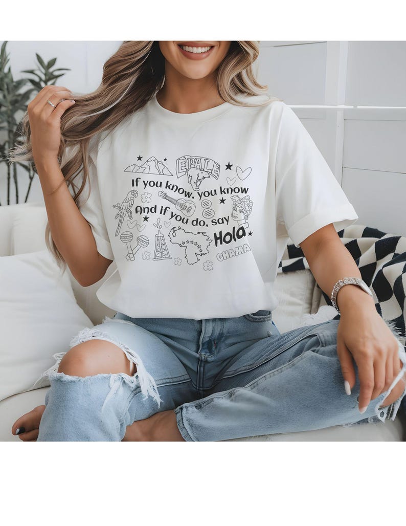 T-shirt with Venezuelan references in form of black and white doodles "el avila", "arepas", venezuelan map "guacamaya", cervical beer beer La Polar sello, "cuatro", "maracas" and Venezuelan lingo like "chama" "epale" , an oil tower, and the saying "if you know, you know And if you do, say Hola"