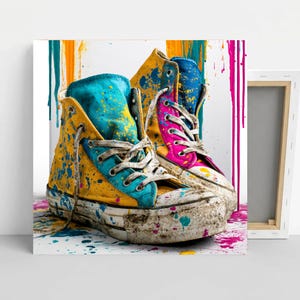 May include: A pair of high-top canvas sneakers featuring a vibrant paint splatter design in yellow, turquoise, and pink. The shoes have white rubber soles and laces, with colorful paint drips extending vertically across the background.