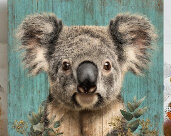 May include: A square wooden panel with a koala bear portrait. The koala has grey fur and brown eyes, set against a distressed teal background. Green foliage is at the bottom. The artwork has a rustic, natural aesthetic, suitable for home decor.