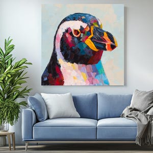 May include: A colorful oil painting of a penguin's head and upper body. The penguin's feathers are depicted with a palette of blues, reds, yellows, and whites. The artwork is displayed on a white wall above a blue sofa.