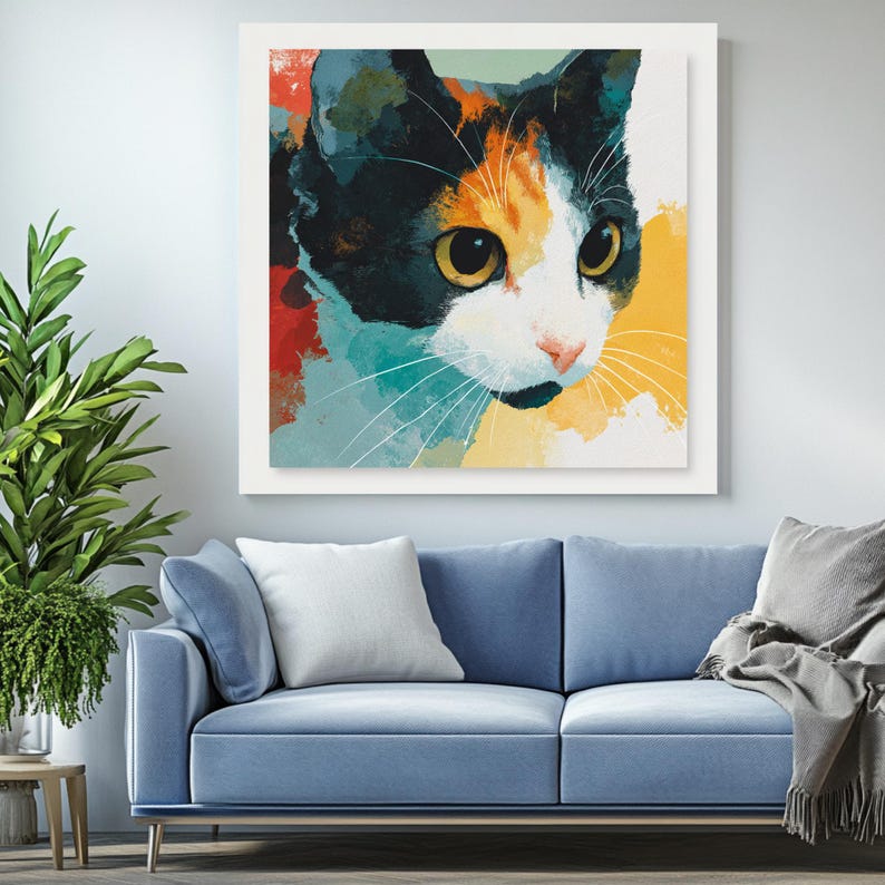 May include: A framed art print depicting a cat's face in an abstract style. The cat has black, orange, and white fur, with large yellow eyes and long white whiskers. The background features splashes of red, blue, and yellow.