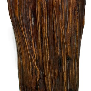 Pode incluir: Um vaso de madeira artesanal com uma superfície texturizada natural. O vaso castanho escuro apresenta riscas castanhas mais claras, criando uma estética rústica. As linhas verticais e a forma orgânica sugerem um design único e artesanal.