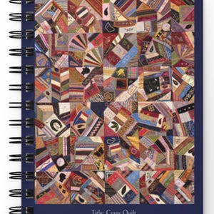 May include: Spiral-bound notebook featuring a colorful Crazy Quilt design. The quilt pattern is composed of various geometric shapes in shades of red, brown, blue, and yellow. The notebook has a dark blue cover with the text "Title: Crazy Quilt" and "Creator: Unknown/ circa 1885".