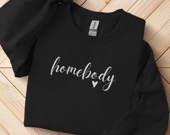 Puede incluir: Sudadera negra con el texto "homebody" en letras blancas cursivas y un pequeño corazón blanco.