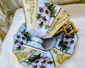 Juego de té vintage Enesco Japan con pedestal, taza y platillo, diseño floral rosa, azul, lustre dorado y geométrico.