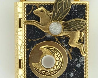 Miniature book necklace featuring an antique gold flying rabbit design on the cover and a story about the moon hidden inside.