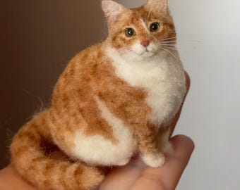 May include: A handmade orange and white cat figurine. The cat is sitting upright with its tail curled. The cat has a white chest and belly, with orange and white stripes on its back and head. The cat's eyes are brown, and its nose is pink.