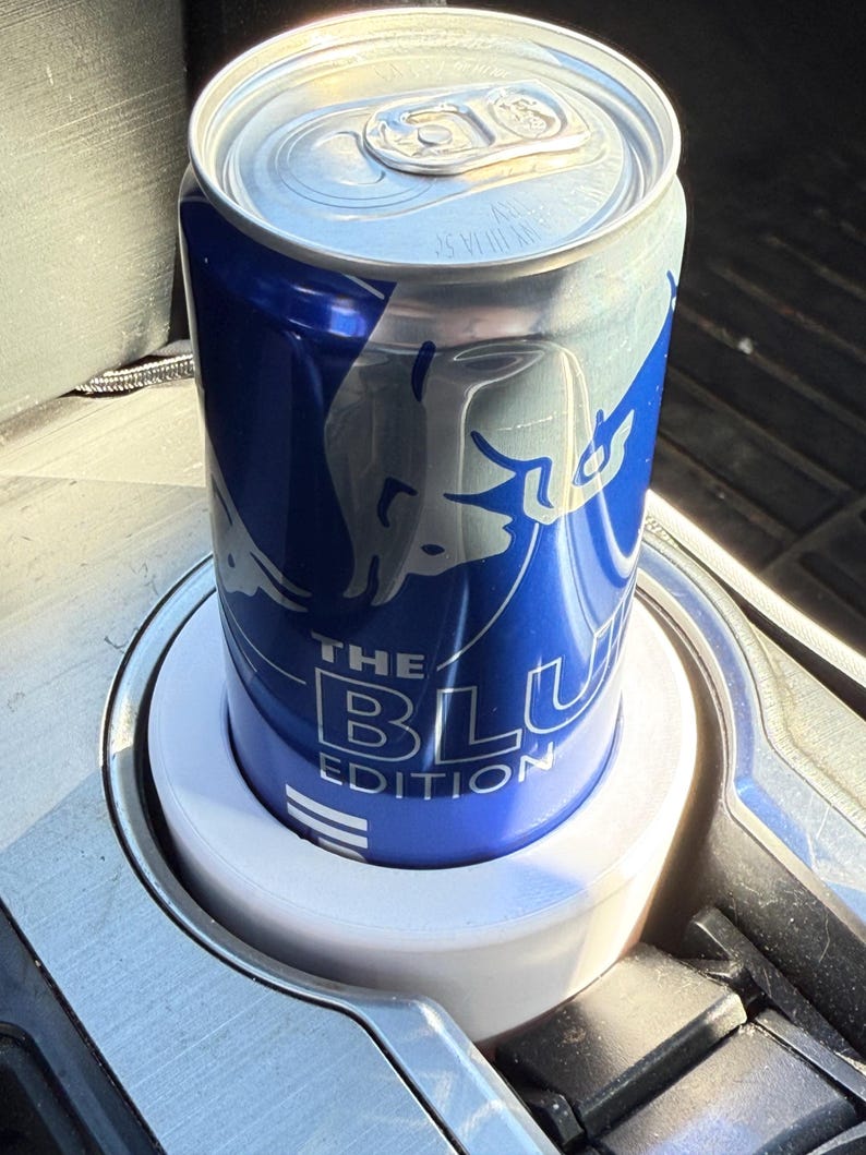 May include: A blue and silver can of Red Bull The Blue Edition in a white cup holder.