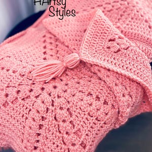 Könnte beinhalten: Eine rosa gehäkelte Decke mit einem Quasten. Die Decke hat ein zartes, durchbrochenes Muster und ist in der Mitte gefaltet. Der Text "HArtsy Styles" ist in der oberen linken Ecke des Bildes sichtbar.
