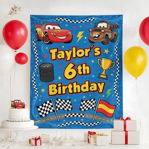 以下が含まれることがあります： 「Taylor's 6th Birthday」の文字と、レーシングカー、タイヤ、旗の画像が描かれた青い誕生日バナー。赤、白、黄色の風船が背景にあり、ケーキとプレゼントも写っています。