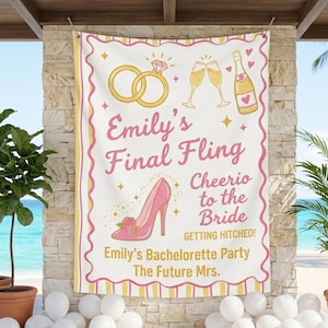 May include: A white banner with pink and yellow accents, featuring the text "Emily's Final Fling" and illustrations of a ring, champagne glasses, and a high heel. The banner reads "Cheerio to the Bride" and "Emily's Bachelorette Party".