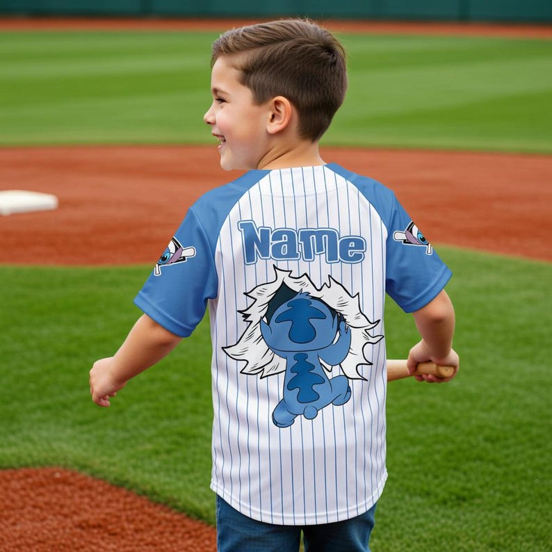 Peut inclure: Un maillot de baseball avec des manches bleues et un corps blanc &agrave; fines rayures bleues. Le maillot porte le nom "Name" en lettres bleues sur le haut du dos et un dessin de personnage de dessin anim&eacute; au bas du dos. Le maillot est port&eacute; par un enfant.