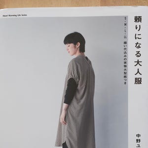 以下が含まれることがあります： 黒い持ち手と「But First, Coffee」のテキストが黒い太字で書かれた白いセラミックマグ。マグは白い表面に置かれています。マグは温かい飲み物に使用される可能性があります。