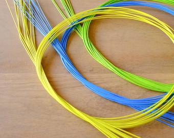 May include: A close-up of three bundles of colourful wire, arranged in a circular pattern. The wires are yellow, green, and blue.