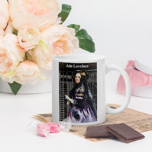 May include: White ceramic mug with a black and white image of Ada Lovelace, a woman in a black dress and white gloves, with the text "Ada Lovelace" at the top.