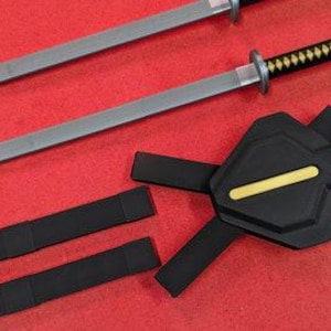 May include: Two silver-bladed katanas with black and yellow handles and a black sheath. The swords are displayed on a red surface, along with a black harness with a yellow stripe.