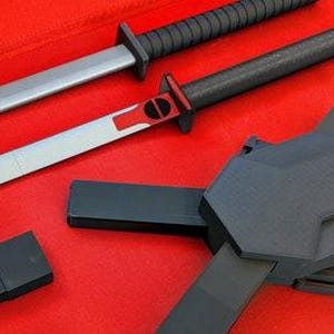 Puede incluir: Dos katanas negras y plateadas con detalles rojos y vainas negras. Las espadas están dispuestas sobre una superficie roja.