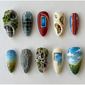 May include: Ten almond-shaped nail art tips featuring diverse designs including textured stone with green moss, blue grid patterns, a red frame, abstract geometric cutouts, colorful vertical stripes, a sunset landscape, gray stone texture, and clouds.