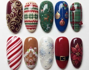 May include: Ten oval-shaped artificial nail tips featuring various holiday designs including gold filigree, a red and green knit pattern, reindeer, Christmas ornaments, plaid, candy cane stripes, a gingerbread house, snowflakes, a Santa belt, and a poinsettia.