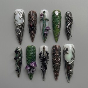 May include: A set of ten press-on nails featuring intricate 3D designs including silver filigree, a spider, a sword with mushrooms, green reptile scales, a centipede, black berries on vines, purple mushrooms, a black scorpion, and a beetle.