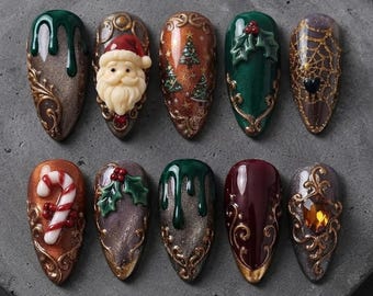 May include: Ten almond-shaped press-on nails featuring Christmas designs including a Santa Claus face, candy cane, holly leaves, gold spiderwebs, pine trees, green drips, and gold filigree accents with embedded rhinestones and metallic finishes.