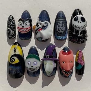 May include: A set of ten press-on nails featuring 3D character designs from The Nightmare Before Christmas, including Jack Skellington, Sally, Zero, and Oogie Boogie, with dark blue glitter backgrounds and hand-painted details like Deadly Night Shade.