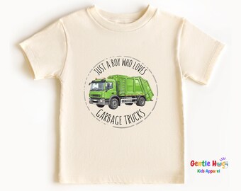 May include: Cream-colored toddler t-shirt featuring a green garbage truck graphic inside a circular design. The text reads "JUST A BOY WHO LOVES GARBAGE TRUCKS". The shirt is made of soft material and is suitable for everyday wear.