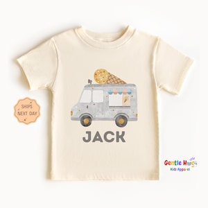 May include: Cream-colored short-sleeved t-shirt featuring a watercolor illustration of an ice cream truck with a large ice cream cone on top. The name "JACK" is printed in gray block letters below the truck. The shirt is from Gentle Hugs Kids Apparel.