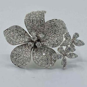 May include: A floral-shaped brooch with a cluster of sparkling, clear gemstones. The brooch features a large, five-petal flower with smaller flower accents. The gemstones cover the entire surface, creating a brilliant, eye-catching design.