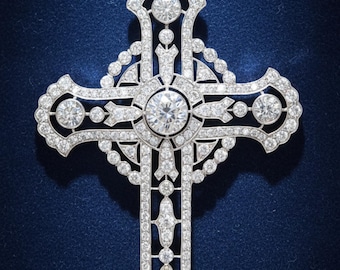 May include: A diamond-encrusted cross pendant with a delicate chain. The cross features a large, central diamond surrounded by smaller stones, with intricate detailing throughout. The pendant is set against a dark blue background.