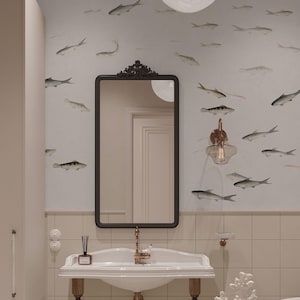 May include: A bathroom with a white sink, a black framed mirror, and a wall decorated with fish illustrations. The sink has a gold faucet and is mounted on a wooden base. A wall sconce with a clear glass shade is mounted on the wall.