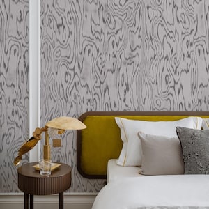 May include: A bedroom with a bed with a yellow headboard and white bedding. The bed has a variety of pillows in different colors and textures. There is a lamp on a side table next to the bed. The wall behind the bed has a gray and white woodgrain pattern.
