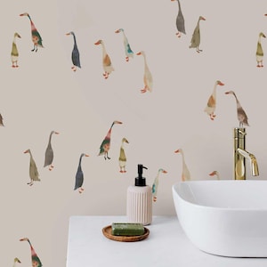 May include: Watercolor geese pattern on a light beige background. The geese are in various colors, including blue, green, and brown. The image is of a bathroom wall with a sink and soap dispenser.