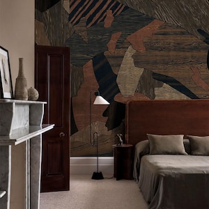 May include: A bedroom interior featuring a large-scale abstract wallpaper with wood grain patterns in shades of brown, black, and tan. The room includes a dark wood door, a tall floor lamp with a white shade, and a bed with a brown headboard.