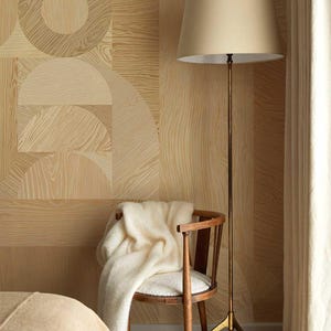 May include: A cozy bedroom scene featuring a wooden chair with a cream-colored blanket draped over it, a tall brass floor lamp with a beige lampshade, and a patterned wood-grain wallpaper. The room has a warm, inviting atmosphere.