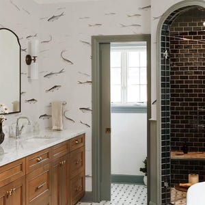 Könnte beinhalten: Ein Badezimmer mit Fischmuster-Tapete, einem Holzwaschtisch mit Marmorplatte und einer schwarz gefliesten Dusche. Der Boden hat ein schwarz-weißes geometrisches Muster. Die Türrahmen sind in einem gedämpften Grün gestrichen.