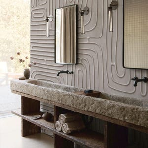 May include: A double bathroom vanity featuring a long, rough-hewn stone trough sink supported by a dark wooden base with open shelving. Two rectangular mirrors with black frames are mounted on a wall with textured, raised vertical line patterns.