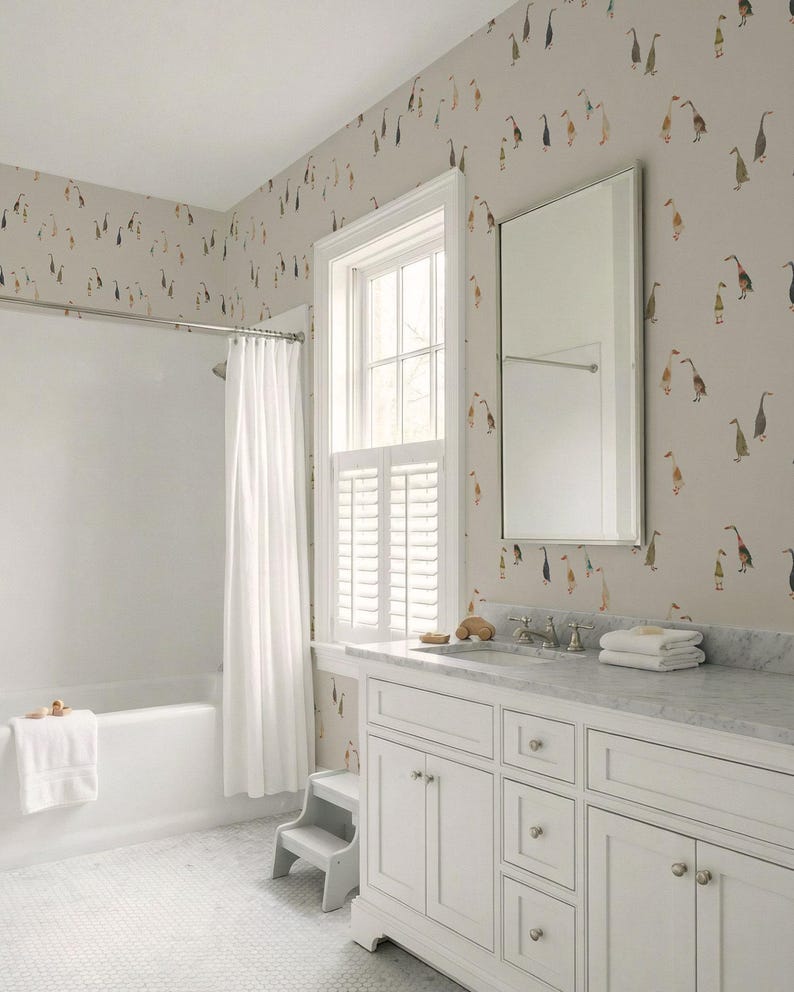 a bathroom with a white bathtub, a white sink with a mirror above it, and a white cabinet below the sink. The walls are covered in a patterned wallpaper with ducks and other birds.