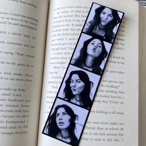 May include: A black and white photo strip bookmark featuring four different photos of a young woman with dark hair. The photos are in a polaroid style with a black border.