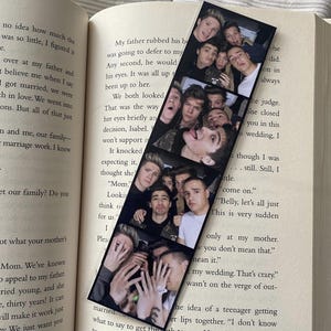 May include: A black and white photo strip bookmark featuring a group of young men smiling and posing for a photo. The bookmark has a white border and is printed on a black background.