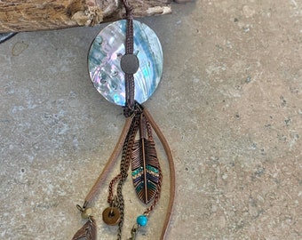 Shell Necklace. Rainbow polished shell disc with adorning copper feathers and leaves. Suede leather and brown cord. Necklace adjusts in size